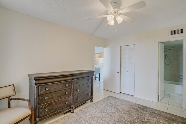 bedroom with visible vents, ceiling fan, light tile patterned floors, ensuite bathroom, and a closet