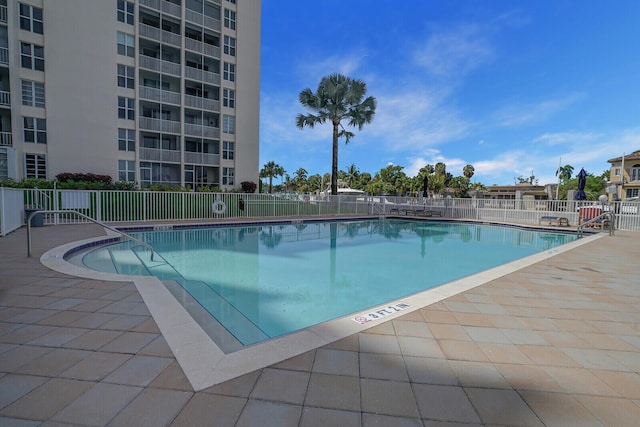 community pool with a patio and fence