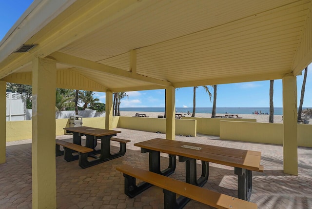 view of patio featuring outdoor dining space, fence, and a water view