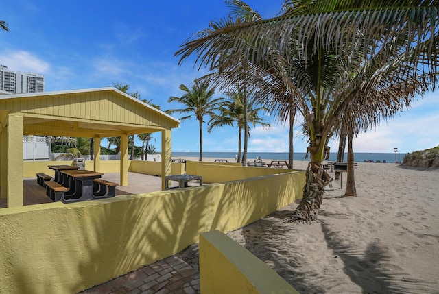 exterior space with a beach view, fence, a water view, and a patio