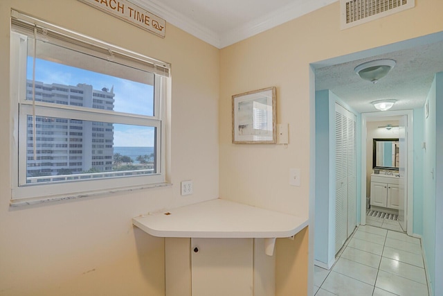 hall featuring light tile patterned floors, visible vents, a textured ceiling, and crown molding