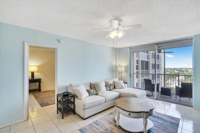 living room with a wall of windows, a textured ceiling, ceiling fan, and light tile patterned flooring