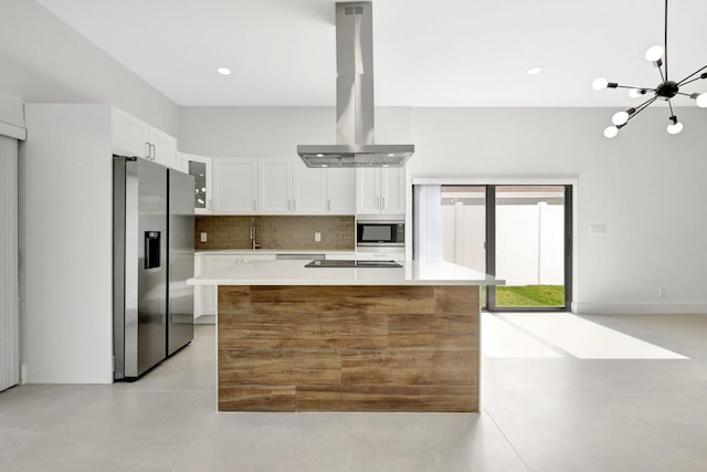 kitchen featuring backsplash, island exhaust hood, stainless steel appliances, white cabinetry, and a sink