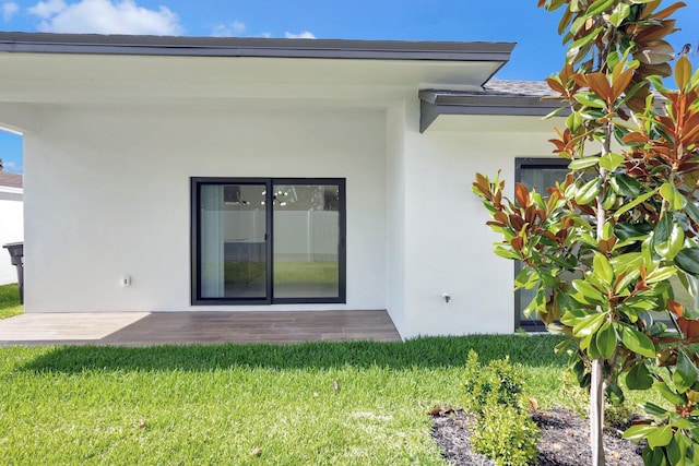 back of house featuring a lawn and stucco siding