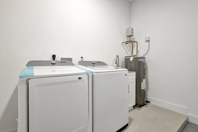 laundry area with baseboards, electric water heater, cabinet space, and washing machine and clothes dryer