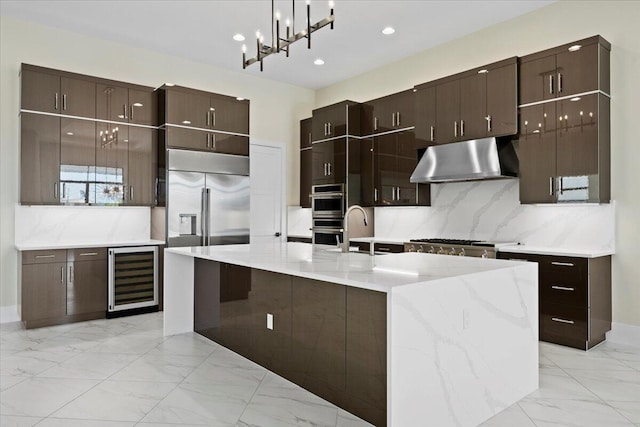 kitchen with wine cooler, under cabinet range hood, marble finish floor, appliances with stainless steel finishes, and backsplash