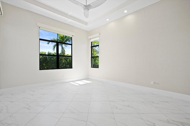 unfurnished room featuring recessed lighting, a raised ceiling, marble finish floor, and baseboards