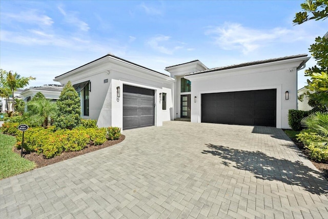 view of front of home with a garage, decorative driveway, and stucco siding