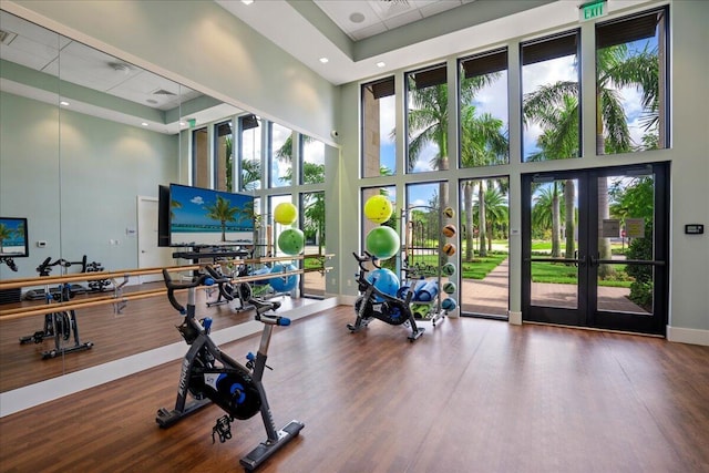 gym with a high ceiling, a drop ceiling, wood finished floors, and baseboards