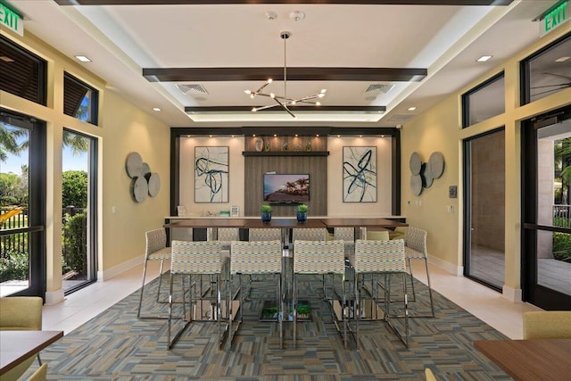 bar featuring baseboards, a tray ceiling, a chandelier, and tile patterned floors