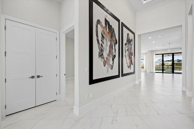 hall with recessed lighting, marble finish floor, and baseboards