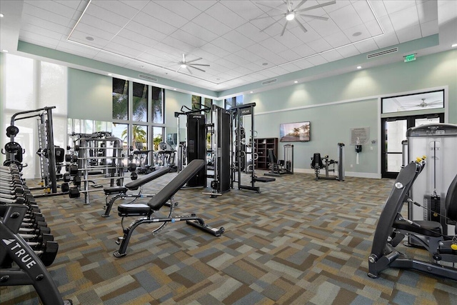 gym featuring carpet floors, a towering ceiling, visible vents, and a ceiling fan