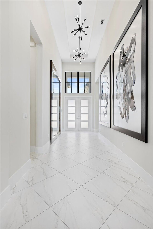 spare room with baseboards, visible vents, marble finish floor, french doors, and a chandelier