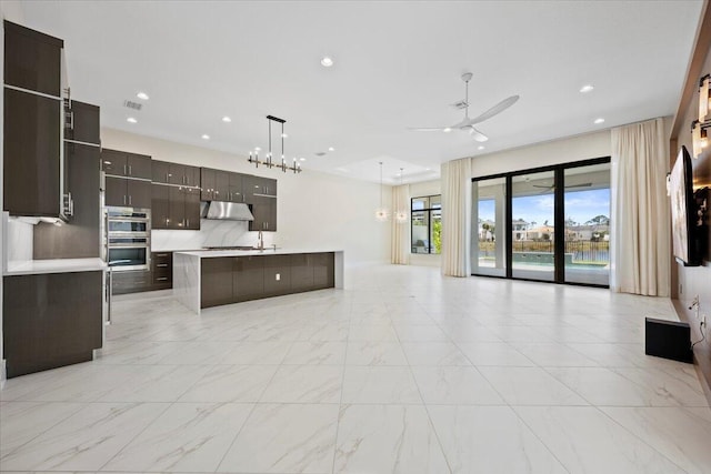 kitchen featuring recessed lighting, light countertops, double oven, open floor plan, and under cabinet range hood