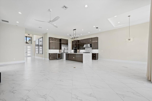 unfurnished living room with baseboards, ceiling fan with notable chandelier, visible vents, and recessed lighting