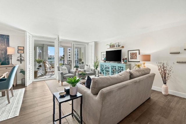 living room featuring baseboards, dark wood-style flooring, and crown molding