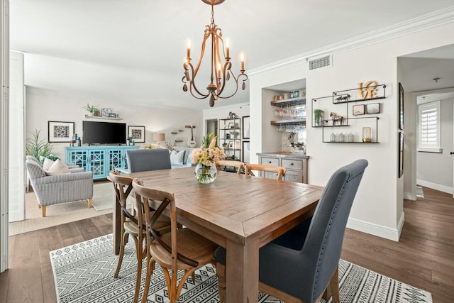 dining room with dark wood finished floors, baseboards, visible vents, a chandelier, and crown molding