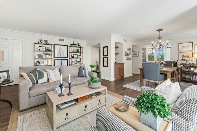 living room featuring wood finished floors, baseboards, visible vents, crown molding, and a chandelier