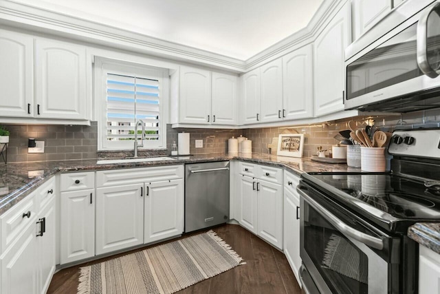 kitchen featuring dark wood-type flooring, decorative backsplash, appliances with stainless steel finishes, white cabinets, and a sink