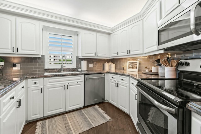 kitchen with decorative backsplash, stainless steel appliances, a sink, and white cabinetry