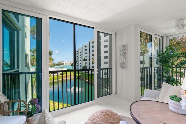 interior space featuring expansive windows, a healthy amount of sunlight, a textured ceiling, and a water view
