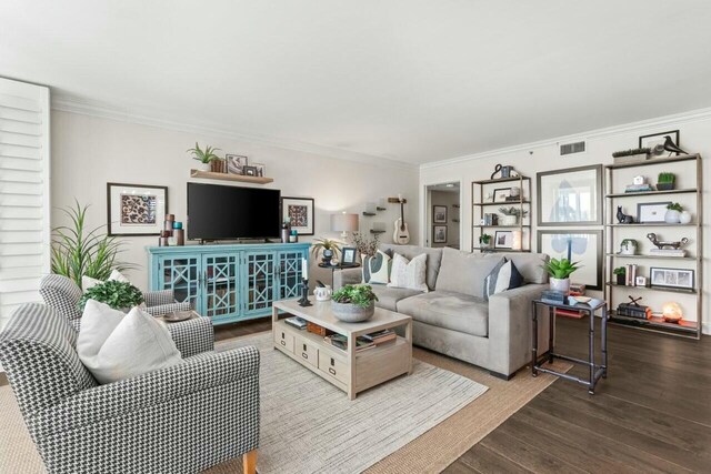 living area with crown molding, wood finished floors, and visible vents