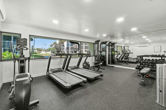 gym featuring recessed lighting, a wall mounted AC, a wealth of natural light, and baseboards