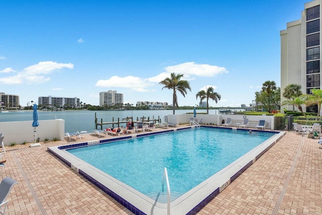 pool featuring a water view, a patio, and fence