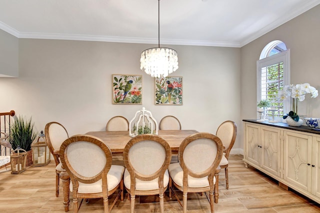 dining space with baseboards, light wood-style flooring, ornamental molding, and a notable chandelier