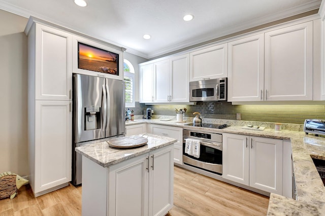 kitchen with white cabinetry, ornamental molding, appliances with stainless steel finishes, light wood finished floors, and tasteful backsplash