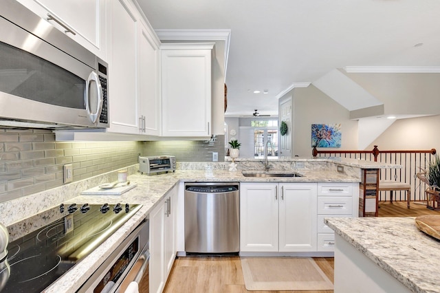 kitchen with light wood-style flooring, appliances with stainless steel finishes, white cabinetry, a sink, and a peninsula