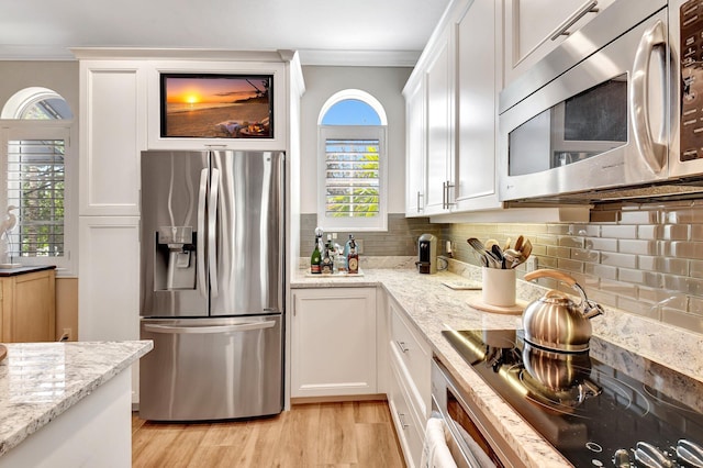 kitchen featuring ornamental molding, appliances with stainless steel finishes, white cabinets, and tasteful backsplash