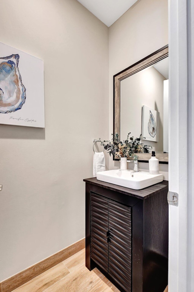 bathroom featuring baseboards, wood finished floors, and vanity