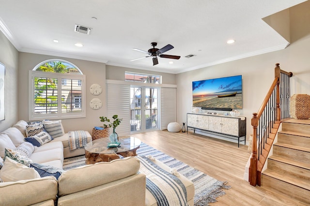 living room featuring stairway, wood finished floors, visible vents, and crown molding