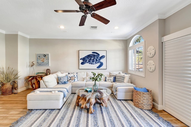 living room with baseboards, visible vents, crown molding, and wood finished floors