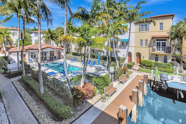 community pool with a boat dock, fence, and a patio