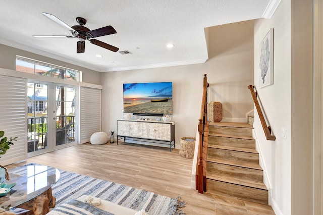 living area with visible vents, wood finished floors, stairs, a textured ceiling, and crown molding