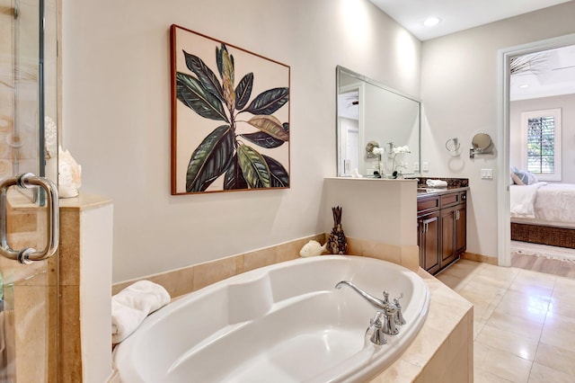 bathroom with vanity, connected bathroom, a bath, and tile patterned floors