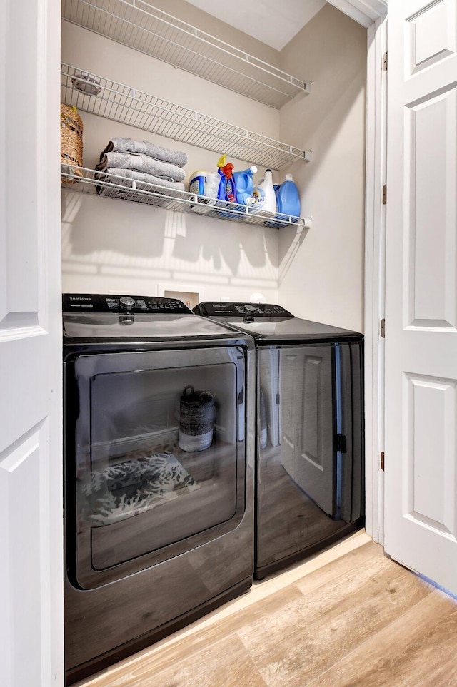 washroom featuring laundry area, wood finished floors, and washing machine and clothes dryer