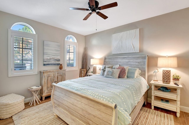 bedroom with a ceiling fan, baseboards, and wood finished floors