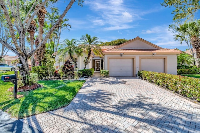 view of front facade with an attached garage, stucco siding, a front lawn, a tiled roof, and decorative driveway