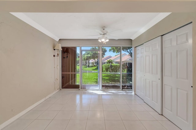 interior space with light tile patterned floors, a ceiling fan, baseboards, and ornamental molding