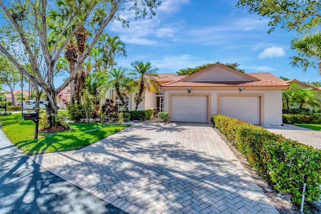 view of front of property featuring a tiled roof, decorative driveway, a garage, and stucco siding