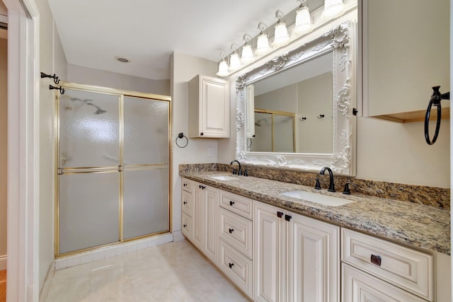 bathroom with tile patterned flooring, a shower stall, double vanity, and a sink