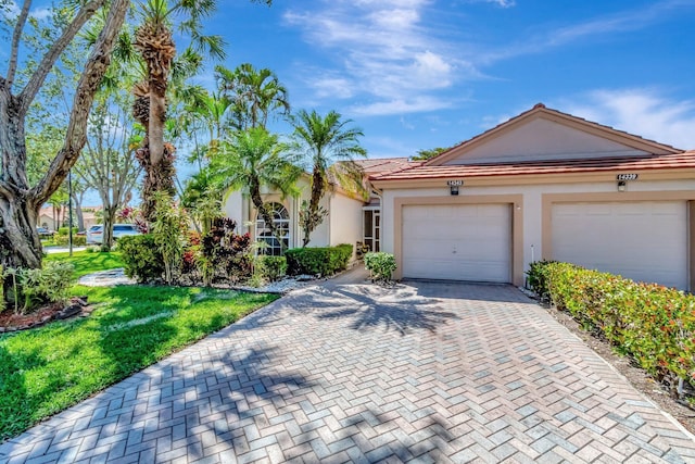 ranch-style house featuring decorative driveway, a garage, a front lawn, and stucco siding