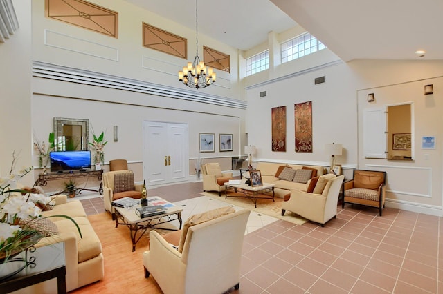 tiled living area featuring visible vents, baseboards, a chandelier, and a towering ceiling