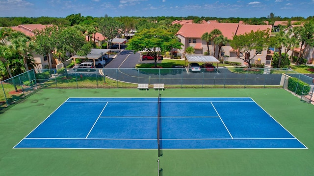 view of tennis court with fence and a residential view