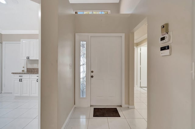 entrance foyer with light tile patterned flooring, baseboards, and ornamental molding