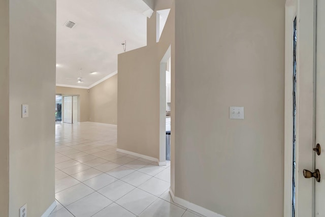 corridor with light tile patterned flooring, visible vents, crown molding, and baseboards