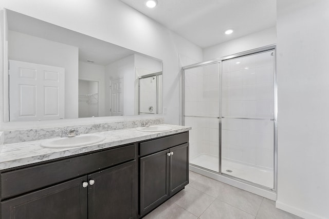 bathroom with tile patterned flooring, a shower stall, double vanity, and a sink